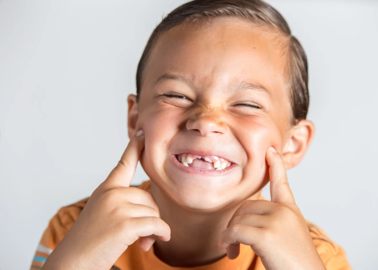 smiling child with missing baby teeth after gentle extraction at pediatric dentist in Bedminster